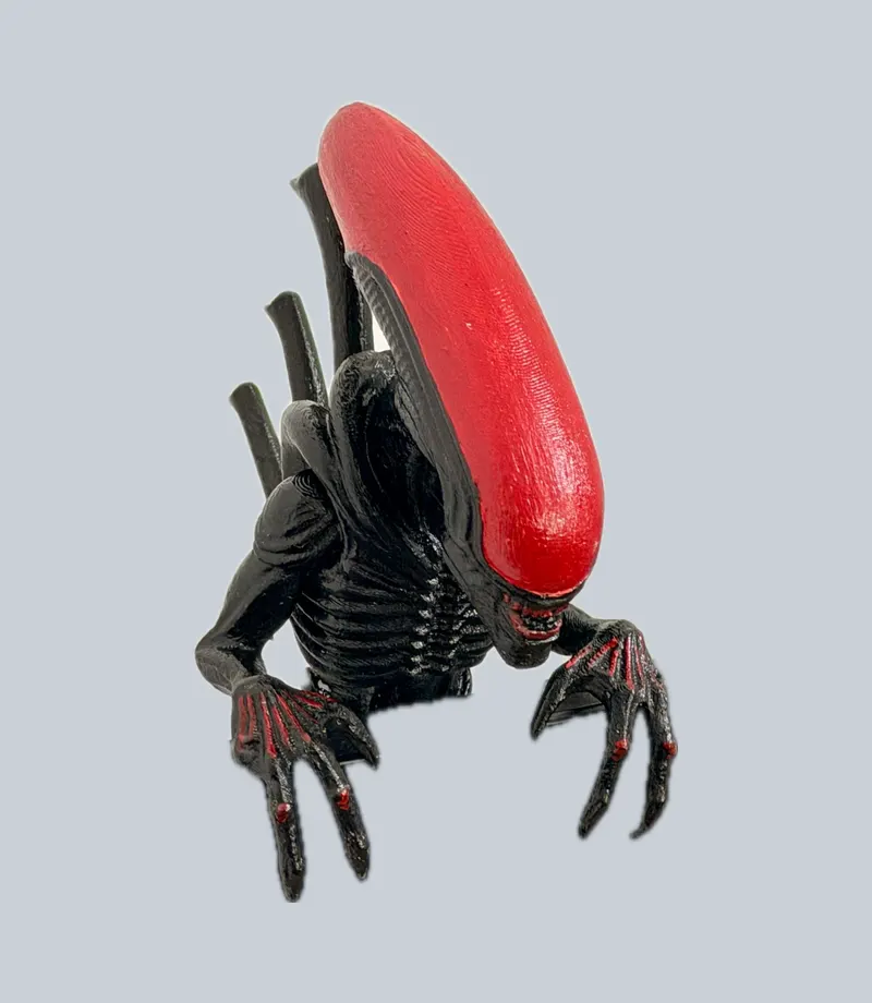 Black creature figurine with a red head and long claws